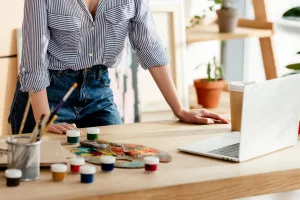 Woman standing in front of laptop ready to paint