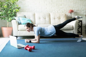 lady doing Pilates in her living room looking at the laptop