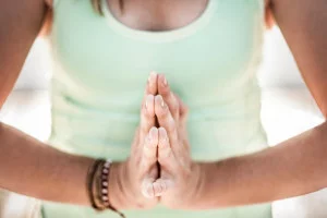 Image of woman with hands in prayer for Yoga nameste